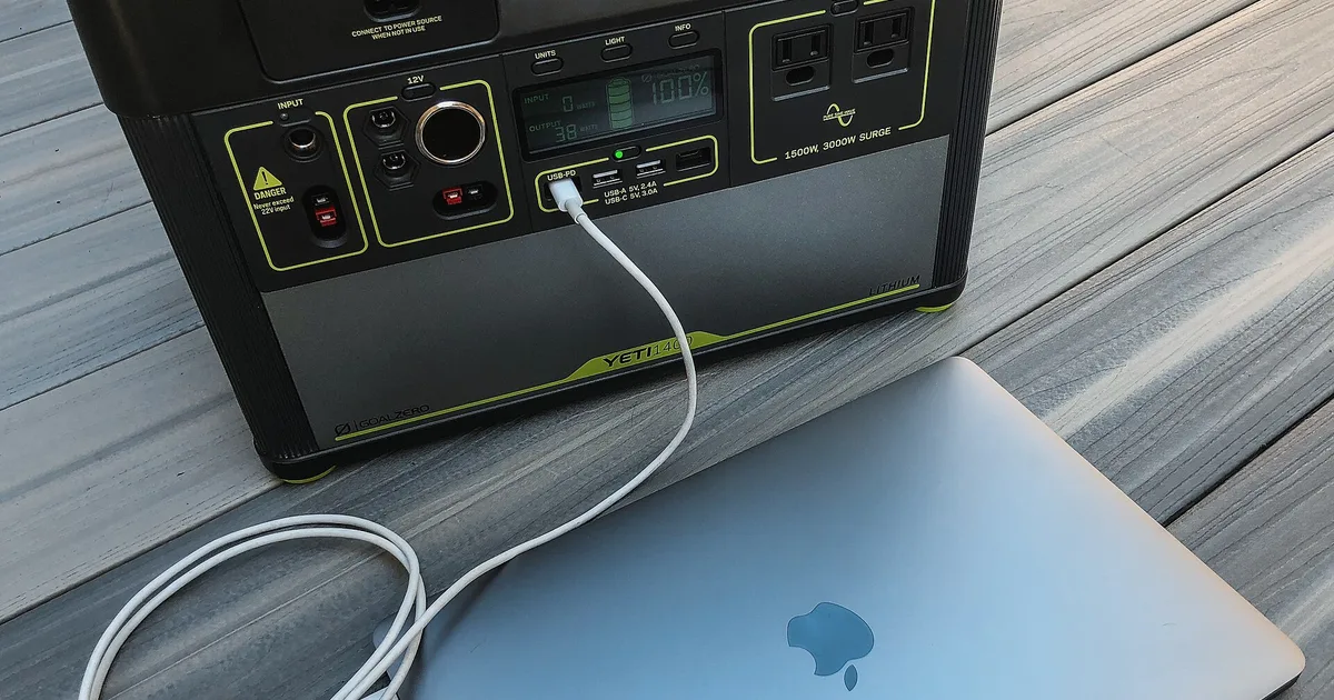 Portable power station charging a laptop on a wooden table during a power cut