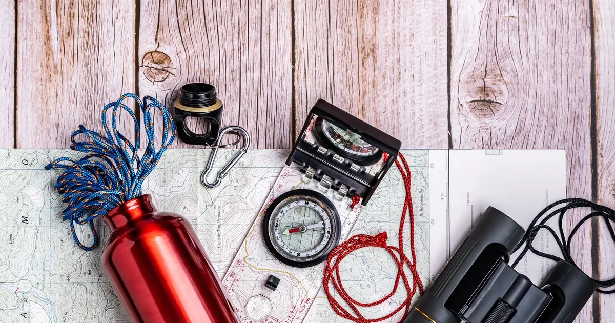 Survival gear and emergency supplies organised on a wooden table for building a 72-hour kit